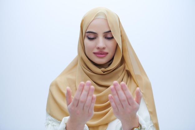 bella donna musulmana in abito alla moda con l'hijab che fa la tradizionale preghiera a Dio, tiene le mani nel gesto di preghiera isolato su sfondo bianco che rappresenta la moda moderna dell'islam e il ramadan karee