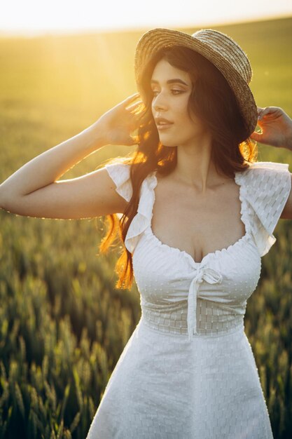 Bella donna nel campo che indossa abito bianco e cappello