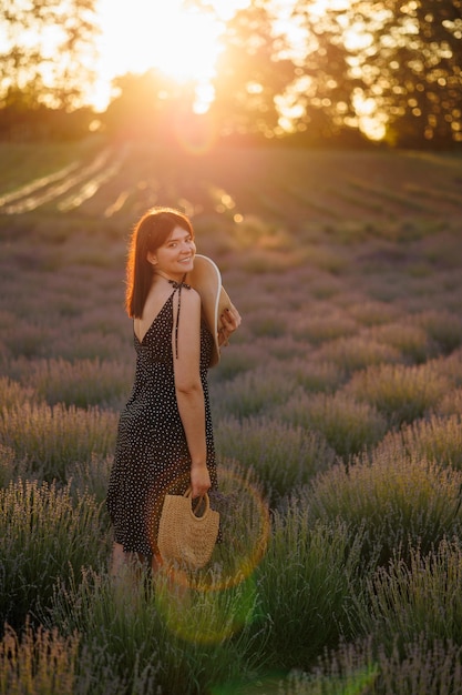 Bella donna nel campo di lavanda al tramonto