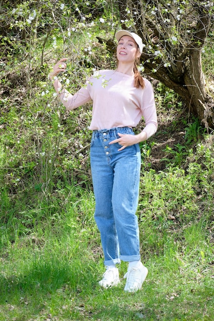 Bella donna nel giardino di primavera in piedi vicino a un albero in fiore