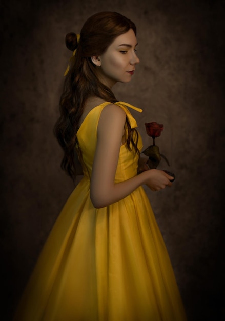 Bella donna nel primo piano del vestito giallo con una rosa rossa nelle sue maniBeauty and the beast cosplay