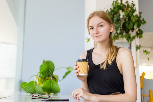 Bella donna nella caffetteria utilizzando il telefono cellulare e mandare SMS nei social network