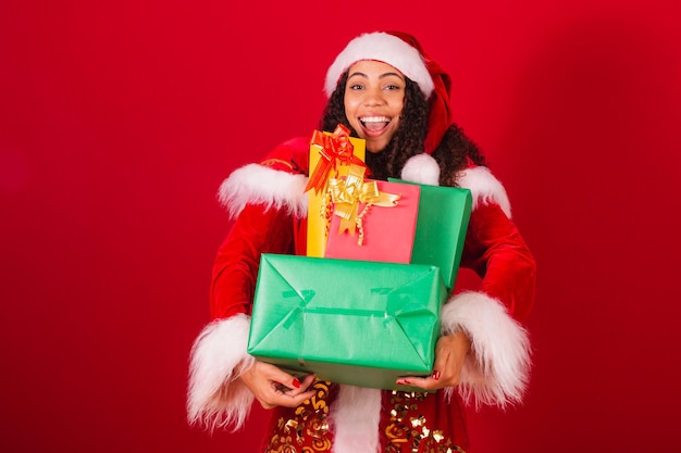 Bella donna nera brasiliana vestita da Babbo Natale vestiti di natale che tengono mucchio con molti regali