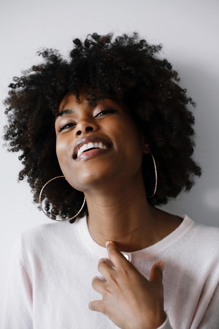 Foto bella donna nera con i capelli afro che sorride sullo sfondo bianco