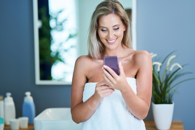 Bella donna nuda con smartphone in bagno