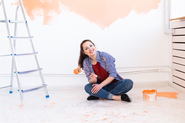 Bella donna pittura muro nel suo nuovo appartamento. Concetto di ristrutturazione e ridecorazione.