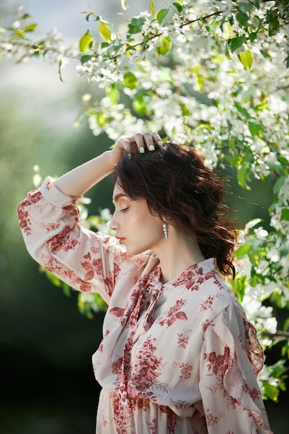 Bella donna romantica si trova in rami di melo in fiore. Ritratto di primavera ragazza in fiori melo