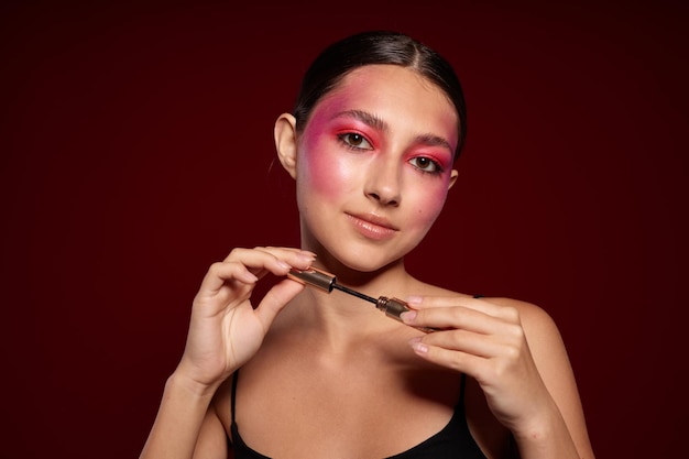 Bella donna rosa trucco viso in posa aspetto attraente cura della pelle sfondo rosa inalterato