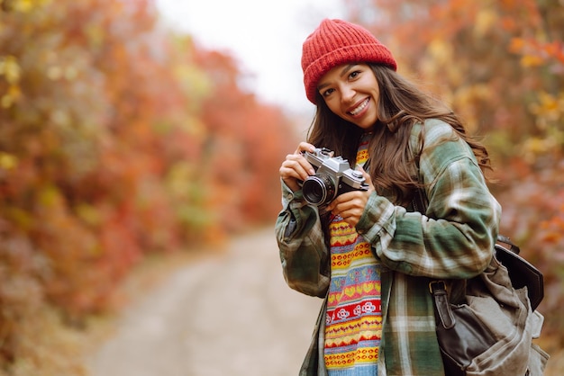 Bella donna scattare foto nella foresta autunnale Sorridente donna che gode del clima autunnale Stile di vita