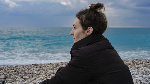 Bella donna seduta da sola sulla spiaggia