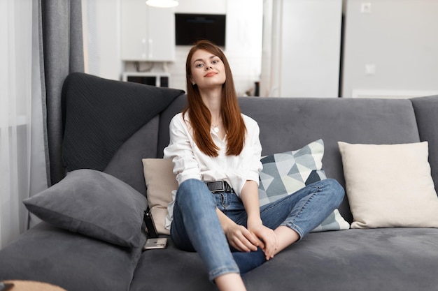 Bella donna seduta in un comodo divano e interni di riposo