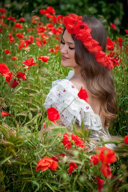 Bella donna seduta nel fiore di papavero