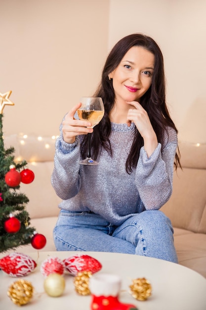 Bella donna seduta sul divano con un bicchiere di vino in mano