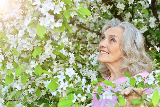 Bella donna senior in piedi vicino all'albero in fiore