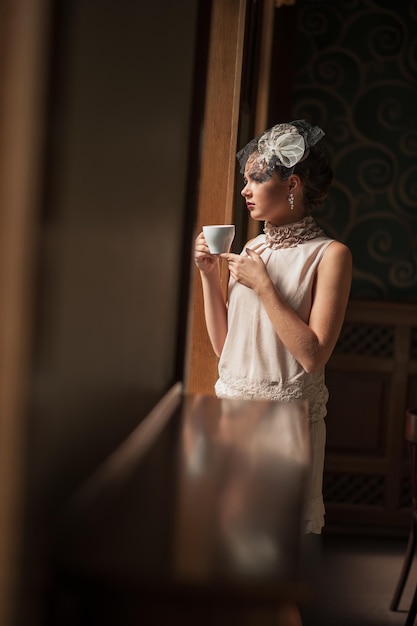 Bella donna sensuale con lunghi capelli scuri in un lussuoso abito di paillettes in posa in un caffè estivo