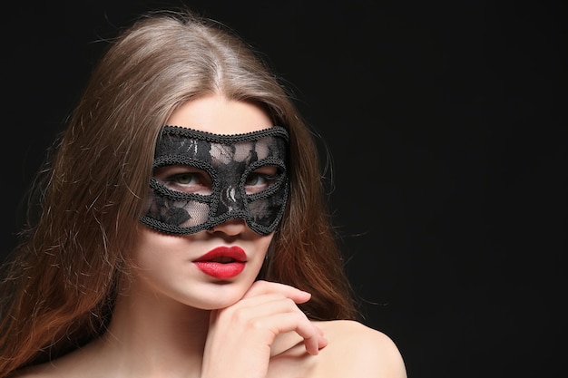 Bella donna sexy con la maschera di carnevale su priorità bassa nera