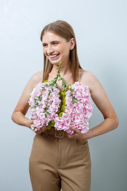 Bella donna sicura di sé che tiene in mano fiori freschi di primavera Fiori freschi nelle mani di una donna dai capelli biondi