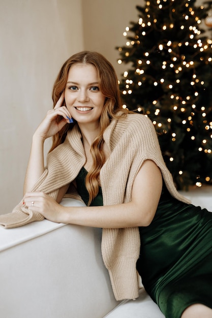 bella donna sorride sullo sfondo di un albero di Natale a casa