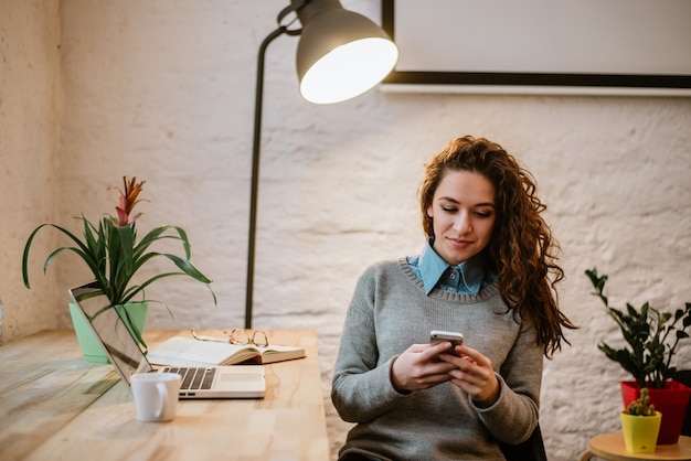 Bella donna sorridente che utilizza il suo telefono nel Ministero degli Interni moderno.