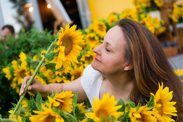 Bella donna sorridente con girasoli gialli luminosi vicino al caffè - negozio di fiori