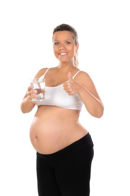 Bella donna sorridente con un bicchiere d'acqua in attesa del bambino