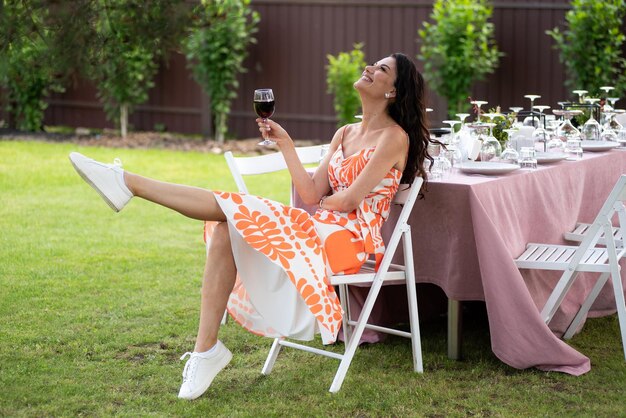 Bella donna sorridente con un bicchiere di vino sullo sfondo estivo