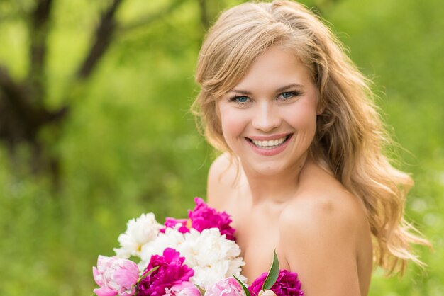 Bella donna sorridente con una corona di peonie sulla testa