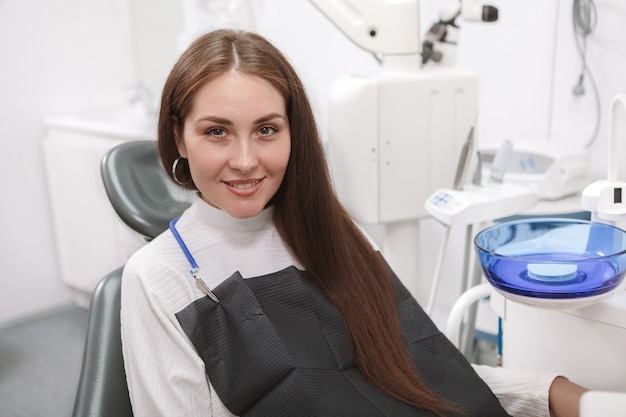 Bella donna sorridente di fronte, seduto in poltrona odontoiatrica