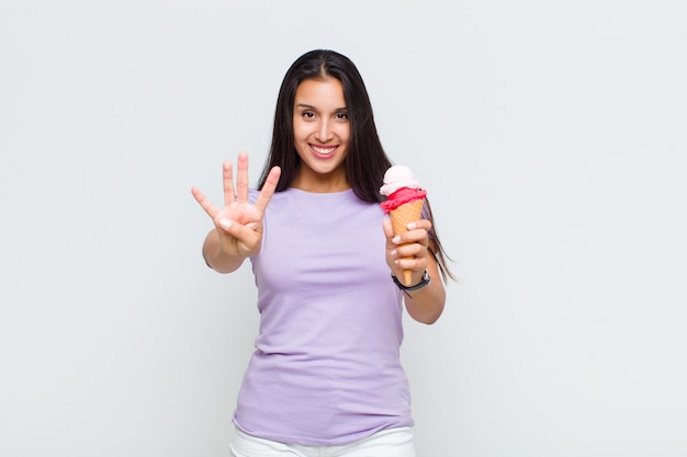 Bella donna sorridente e dall'aspetto amichevole, mostrando il numero quattro o quarto con la mano in avanti, conto alla rovescia