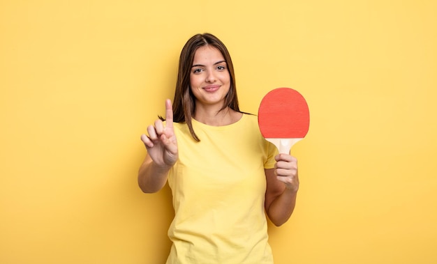 bella donna sorridente e dall'aspetto amichevole, mostrando il numero uno. concetto di ping pong