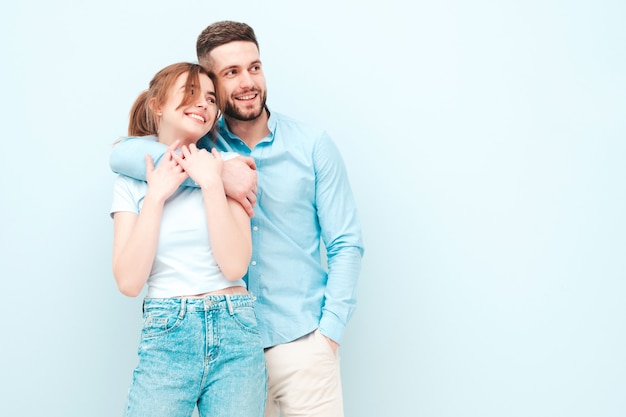 Bella donna sorridente e il suo bel ragazzo. Famiglia allegra felice che ha momenti teneri vicino al muro azzurro in studio