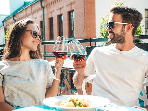 Bella donna sorridente e il suo bel ragazzo Famiglia allegra felice Coppia tifo con bicchieri di vino rosso al loro appuntamento nel ristorante Bevono alcolici al caffè veranda in strada