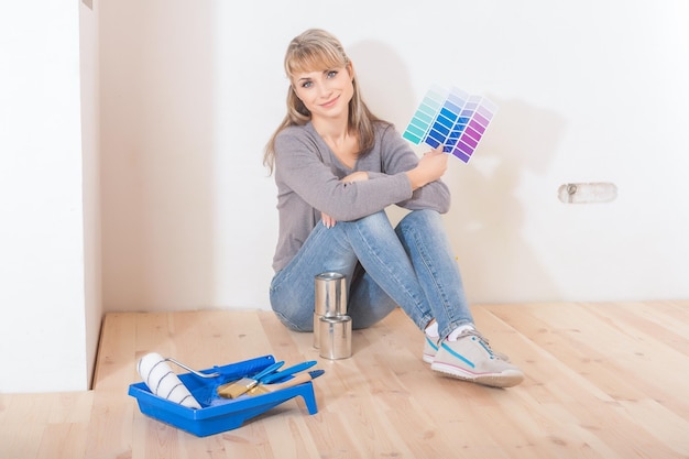 Bella donna sorridente seduta sul pavimento con strumenti di pittura e tavolozza dei colori