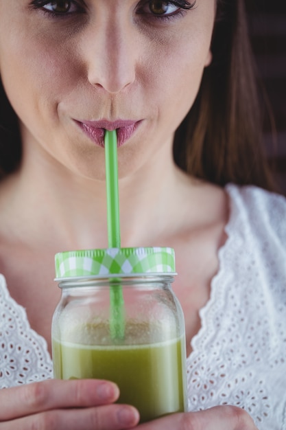 Bella donna sorseggiando succo verde