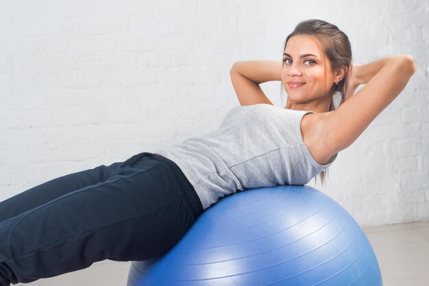 Bella donna sportiva che fa esercizio di fitness che si estende sulla palla Pilates mette in mostra la salute