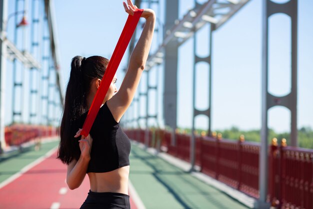 Bella donna sportiva che fa formazione con elastico di resistenza su un ponte. Spazio per il testo