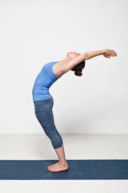 Bella donna sportiva in forma pratica Sivananmda yoga asana Anuvittasana in piedi piegare la posa