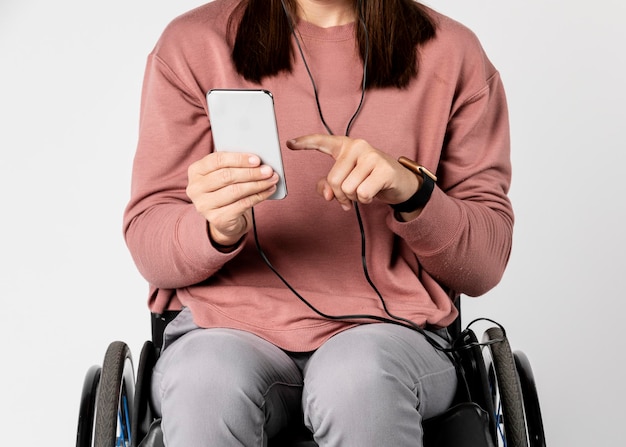 Bella donna su una sedia a rotelle che ascolta musica
