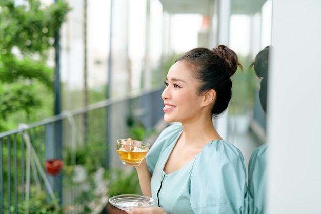 Bella donna sul balcone che beve il tè