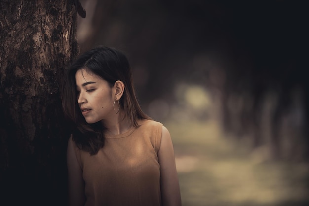 Bella donna tailandese molto triste per l'amore non corrisposto, ripensando allo stile vintage, tono scuro, ragazza asiatica con il cuore spezzato