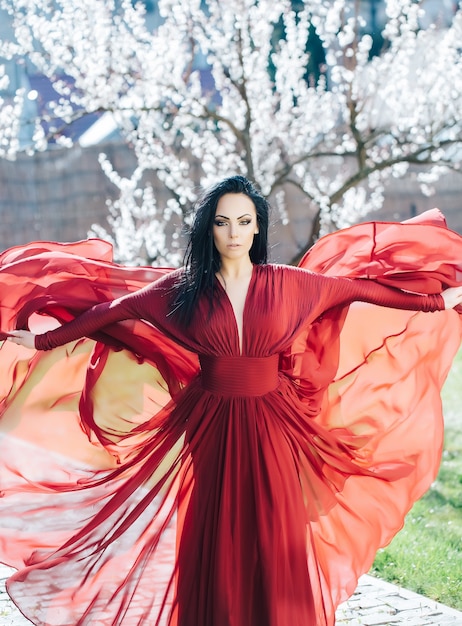 Bella donna vicino all'albero di fioritura Bellezza e moda di primavera