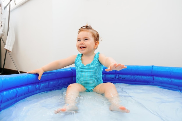 Bella e carina bambina felice che si diverte nella piccola piscina di casa