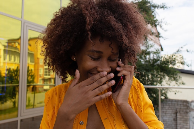 bella e felice afroamericano in strada con il suo telefono