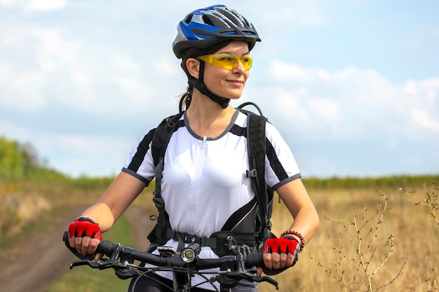 Bella e felice donna ciclista con una bici sulla natura. Stile di vita sano e sport. Tempo libero e hobby
