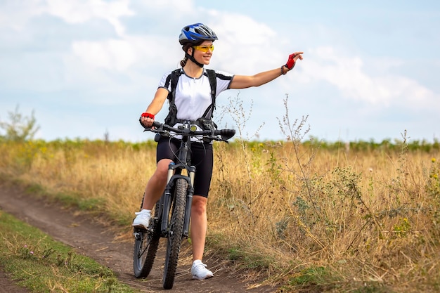 Bella e felice donna ciclista con una bicicletta sulla natura. Stile di vita sano e sport. Tempo libero e hobby