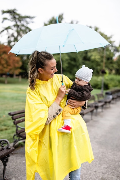 Bella e felice donna di mezza età con il suo bambino che cammina nel parco cittadino in una giornata piovosa