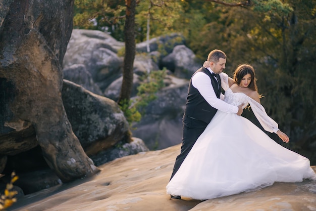 Bella e felice sposa e sposo che ballano all'aperto sulla roccia