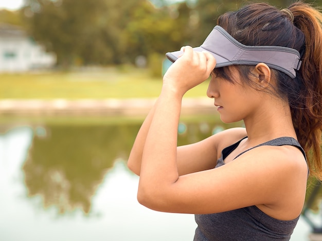 Bella e forte donna runner si prepara e tocca il suo berretto sportivo