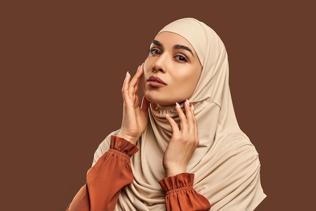 bella e moderna donna musulmana naturale trucco vestita in beige hijab cura della pelle del viso bellezza femminile