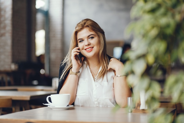 bella ed elegante ragazza seduta in un caffè e bere un caffè